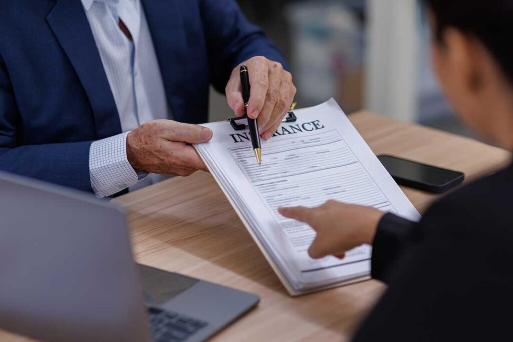 A couple reviews legal and insurance documents at a kitchen table after separation.