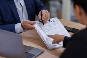 A couple reviews legal and insurance documents at a kitchen table after separation.